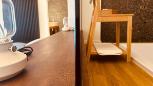 Ein Badezimmer mit Holzboden, einem Holzstuhl, einem Waschbecken und einem Spiegel.