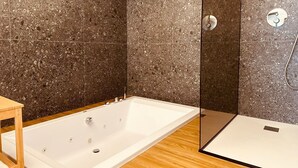 Ein modernes Badezimmer mit einer freistehenden Badewanne, einer Duschkabine aus Glas und einem Holzbadezimmermöbel.