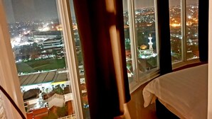 Una stanza con un'ampia finestra che si affaccia su un panorama cittadino notturno, con edifici illuminati e una cupola imponente.