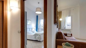 A hotel room with a bed, a sofa, a table with a cactus, and a window with curtains. - White Lion - Harmonious apartment near Santa Maria Novella (Florence)