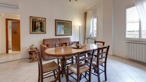 A dining area with a wooden table and chairs, a sofa, and two paintings on the wall. - White Lion - Harmonious apartment near Santa Maria Novella (Florence)