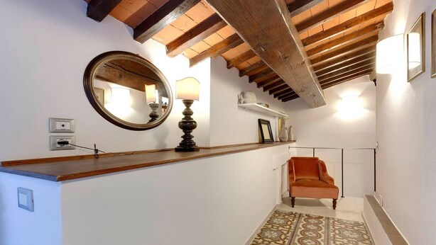 A hallway with a wooden counter, a round mirror, a lamp, and a patterned floor. - White Lion - Harmonious apartment near Santa Maria Novella (Florence)