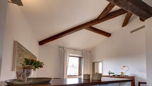 A kitchen with a wooden ceiling, a window with white curtains, and a vase with flowers on the counter. - Green Dragon - Bright apartment with Arno view (Firenze)