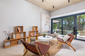 A modern living room with wooden shelves, a round coffee table, and two leather chairs. - Villa Mol - A stunnung contemprary villa with large private pool, hot tub and sauna, just a short drive from the sea (Baderna)