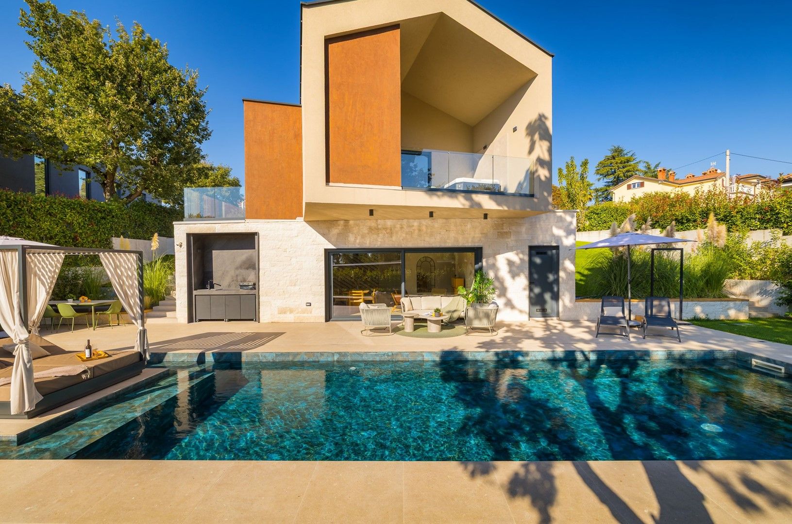 Una casa moderna con piscina, mobiliario exterior y un patio cubierto.