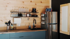 A modern kitchen with wooden walls, a stainless steel refrigerator, and a wooden countertop.