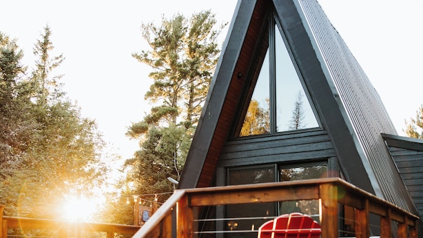 A wooden deck with a red Adirondack chair, a staircase, and a modern building with a triangular roof.
