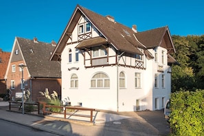 Un bâtiment traditionnel à colombages, doté d’un balcon, d’une entrée pavée et d’un banc.