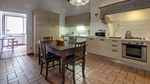 A kitchen with wooden cabinets, a dining table with chairs, a hanging light fixture, and a tiled backsplash. - Niche - View of the Buontalenti Lantern (Florence)