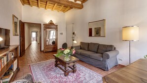 A living room with a sofa, a coffee table with flowers, a TV, and a bookshelf. - Niche - View of the Buontalenti Lantern (Florence)