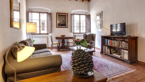 A cozy living room with a sofa, coffee table, and a television on a wooden stand. - Niche - View of the Buontalenti Lantern (Florence)