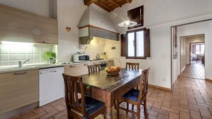 A kitchen with wooden cabinets, a dining table with chairs, and a hanging light fixture. - Niche - View of the Buontalenti Lantern (Florence)