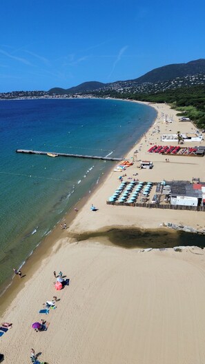 A beach with clear blue water, a pier, and a row of beach umbrellas. - La Maison du Jardin de Gassin Nature and serenity (Gassin)