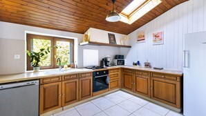 A kitchen with wooden cabinets, a dishwasher, a stove, and a microwave. - Gite O Pré'Vert, Gîte Ô Pré'Vert. Group gite, tourist rental in Le Poiré Sur Vie in the Vendée. G... (Le Poiré-sur-Vie)