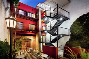 A multi-level building with a red facade, a staircase, outdoor seating area, and a checkered floor pattern. - Mariposita de San Telmo Hotel Boutique (Buenos Aires)