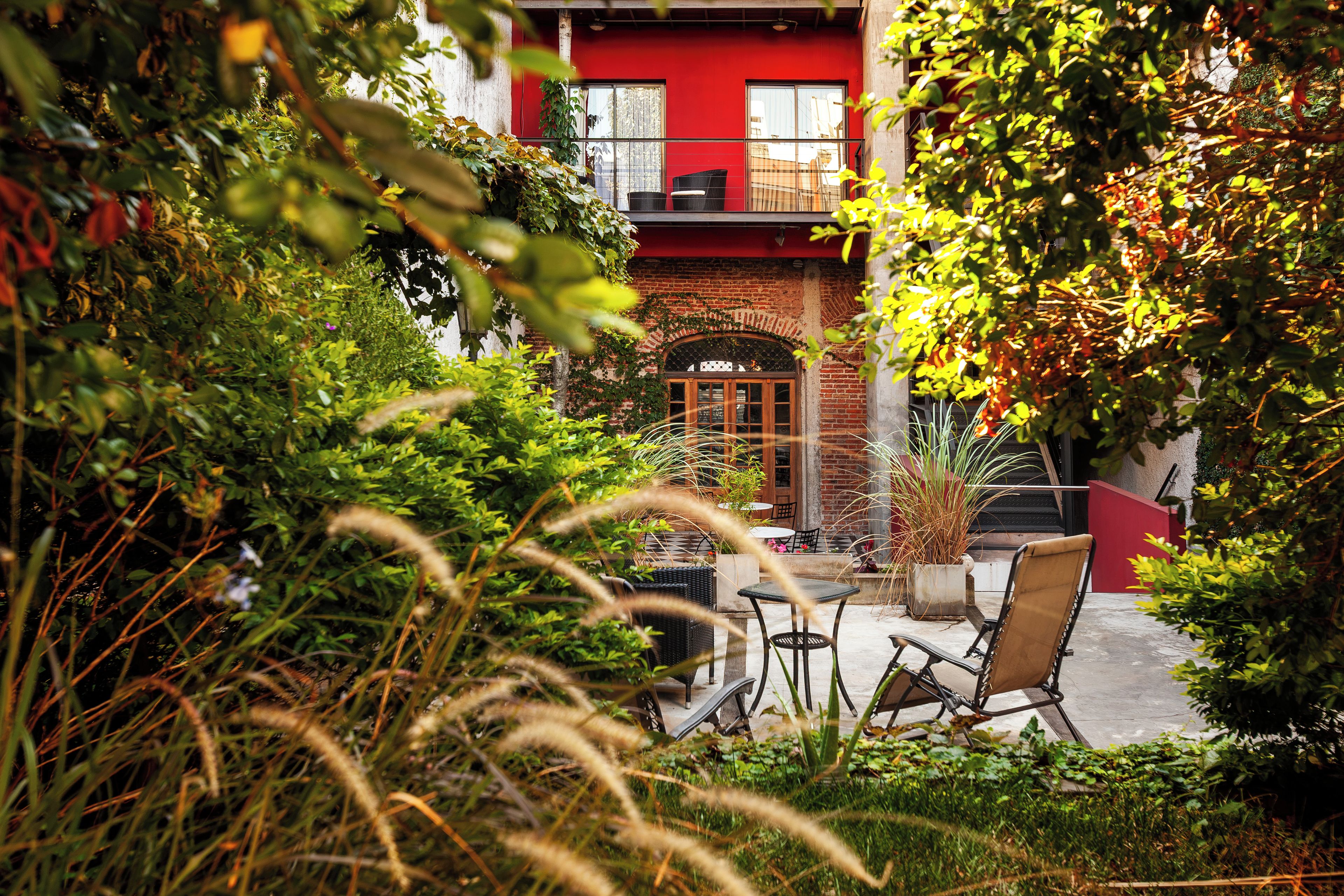A courtyard with a red building, a brick archway, and outdoor furniture.