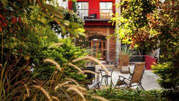 A courtyard with a red building, a brick archway, and outdoor furniture.