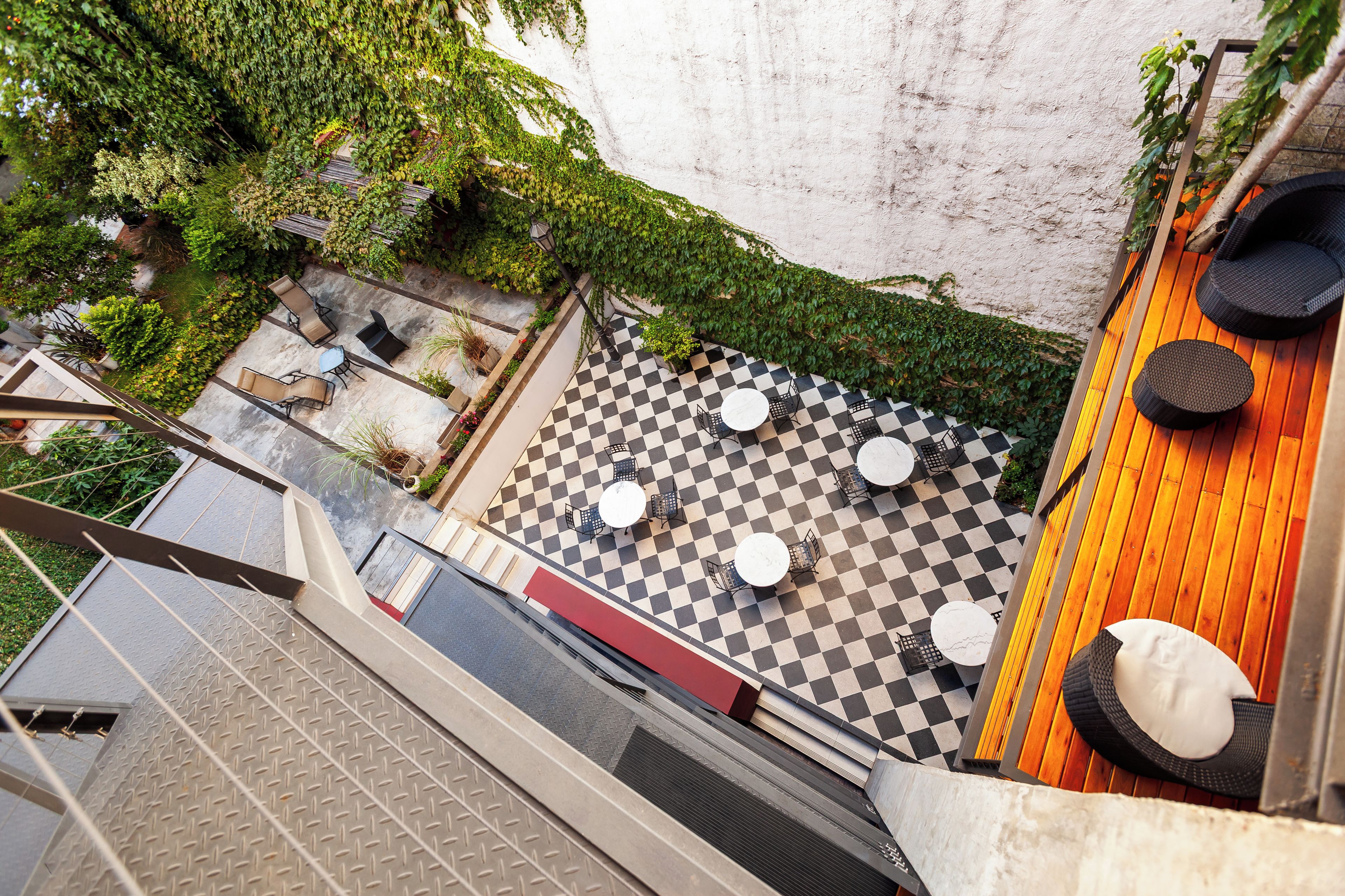 A rooftop terrace with checkered flooring, outdoor seating, and greenery.