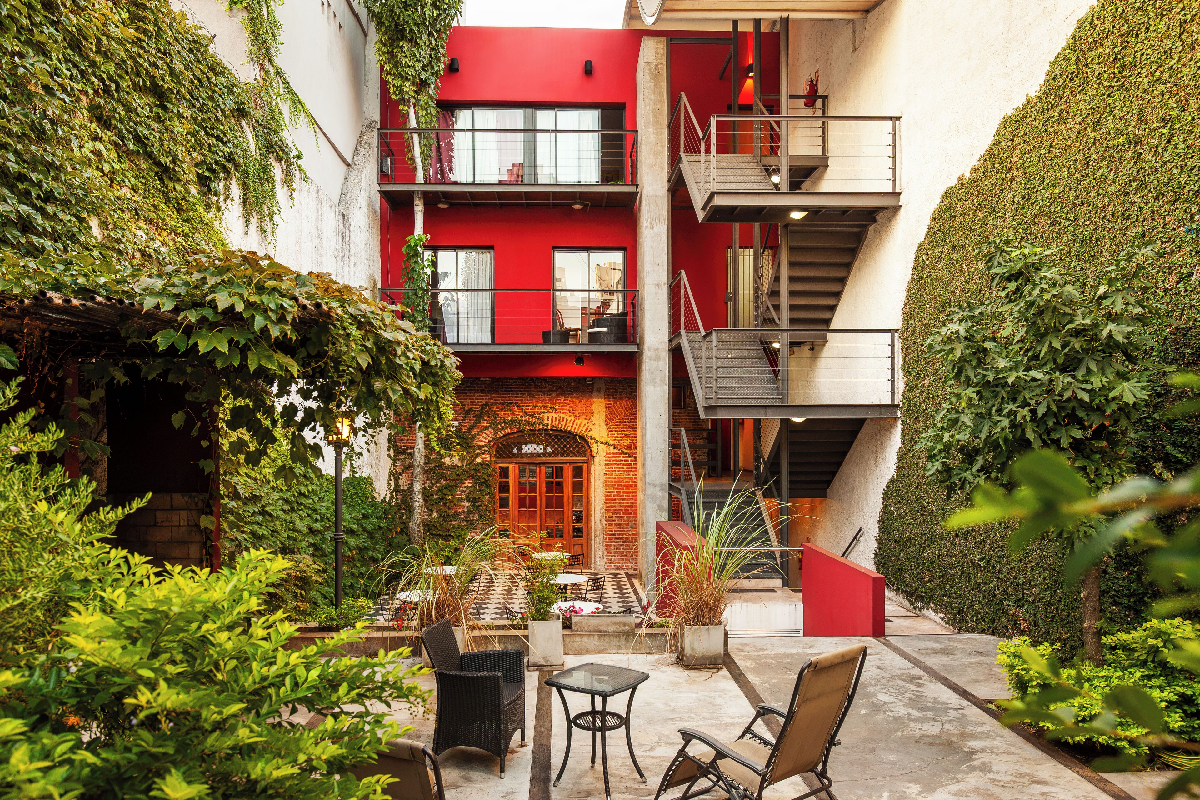 A courtyard with a red building, a staircase, and outdoor seating.