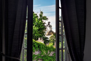 A view through a window with curtains, featuring a building with a dome and a tree with green leaves. - Mariposita de San Telmo Hotel Boutique (Buenos Aires)