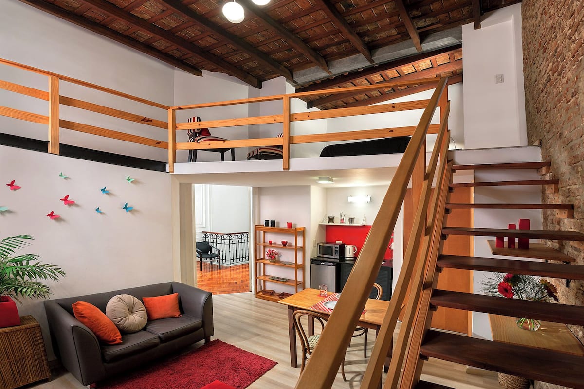 Un espacio habitable estilo loft con escalera de madera, zona de comedor y cocina.