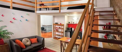 Ein Loft-Wohnbereich mit einer Holztreppe, einem Essbereich und einer Küche.