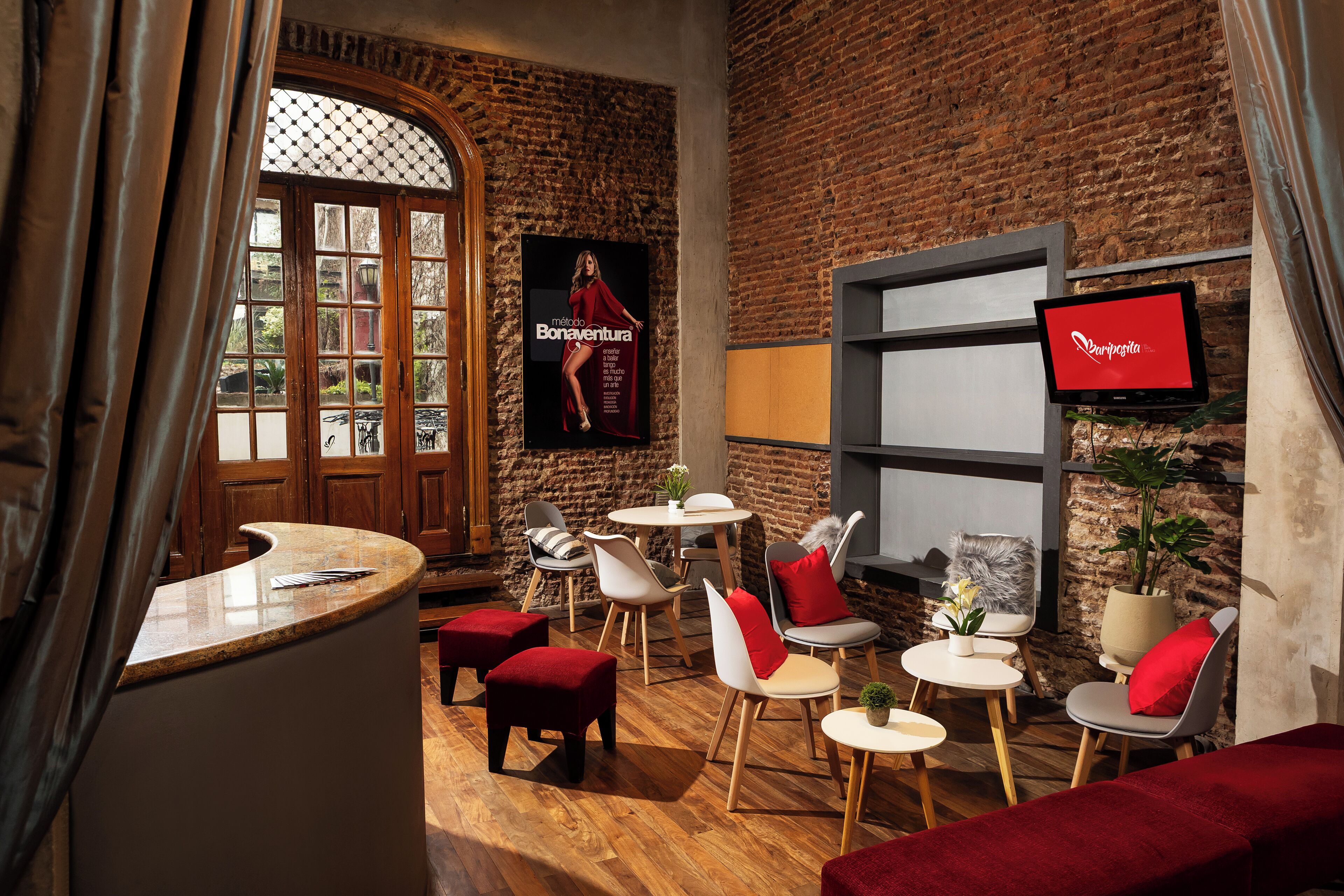 Un interior acogedor con pared de ladrillo, suelo de madera y una mezcla de muebles modernos y clásicos.