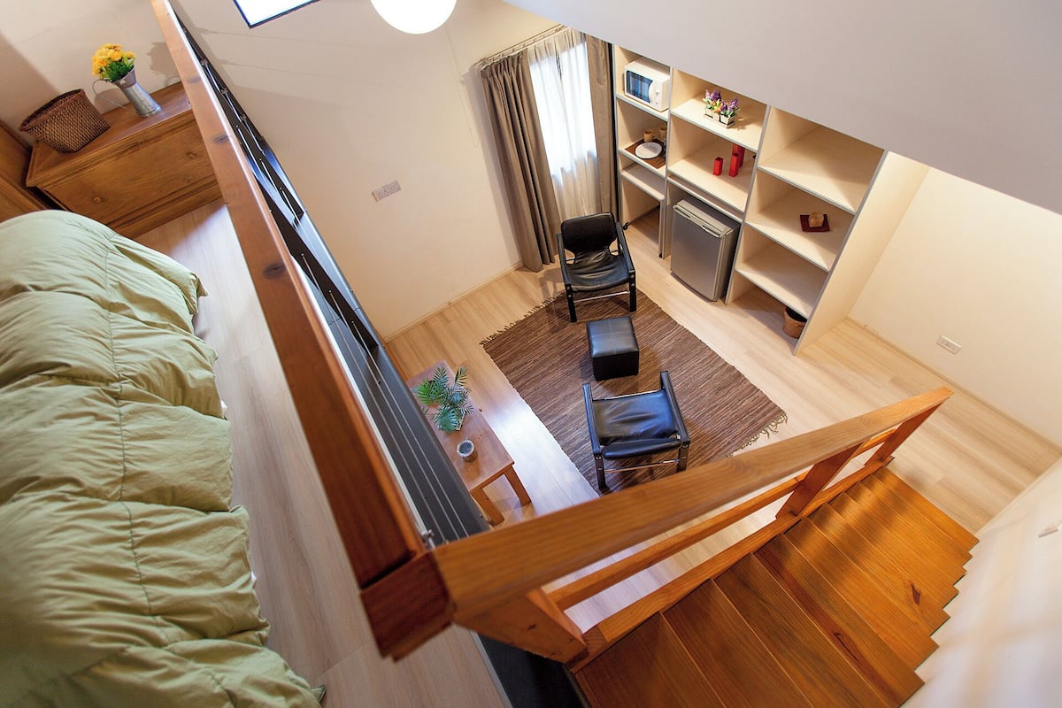 Un dormitorio con cama, escritorio, silla y una mesita.