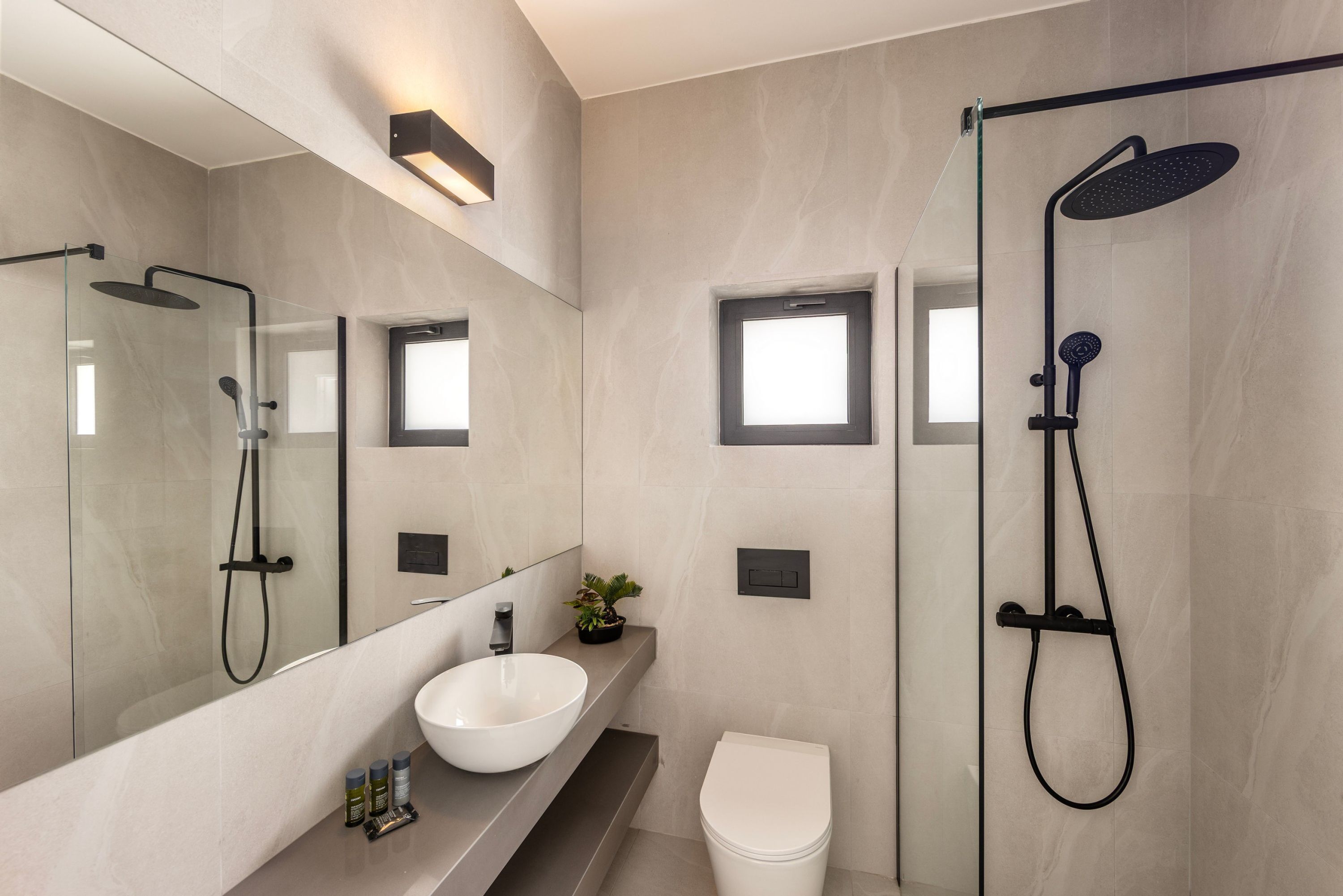 A modern bathroom with a glass-enclosed shower, a white sink, and a large mirror.