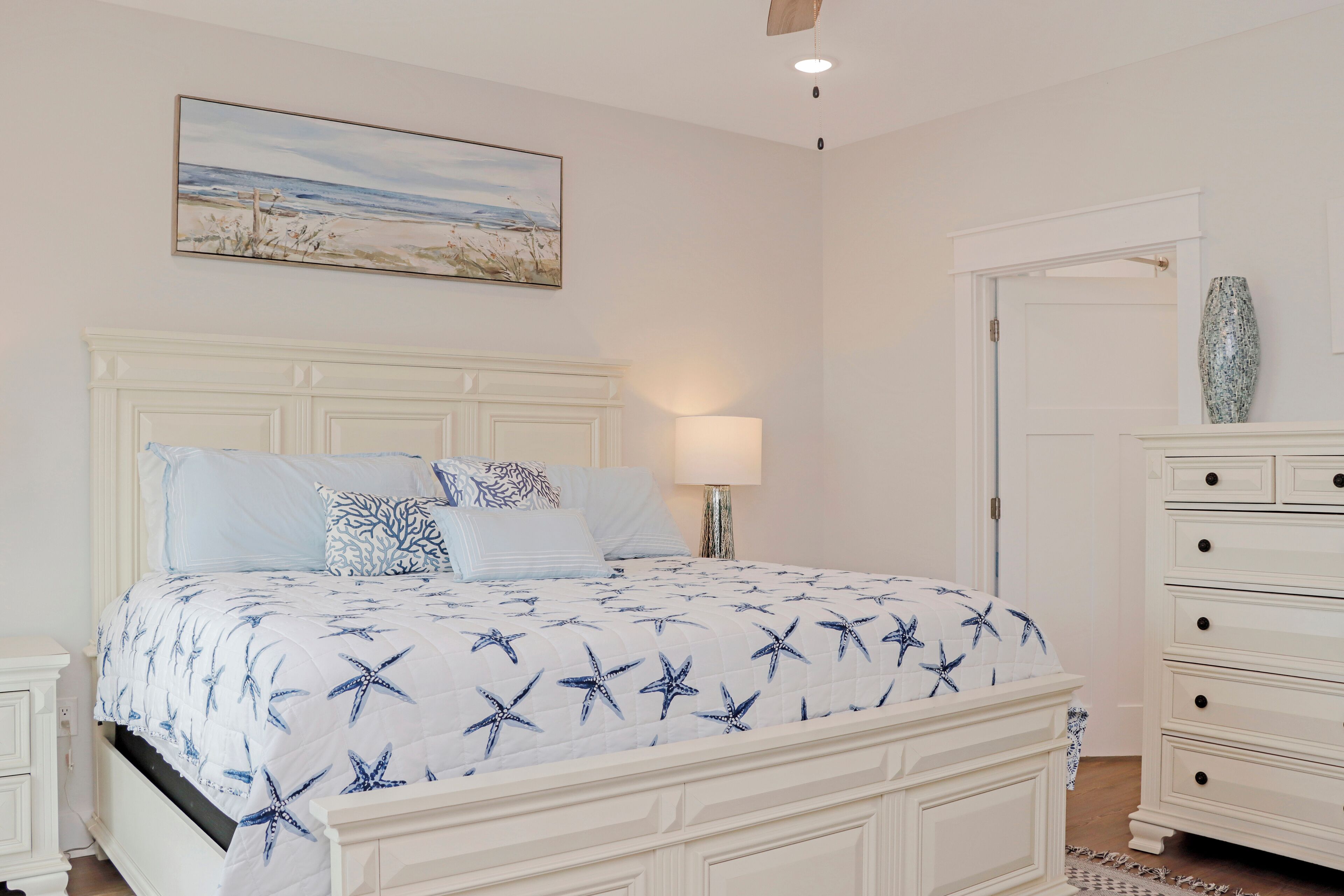 Une chambre à coucher avec un lit, une table de chevet, une commode et un tableau au mur.