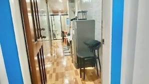 A corridor with a checkered floor, a refrigerator, and a chair. - Room-lens Staycation IN Panabo 1bdr BR (Davao)