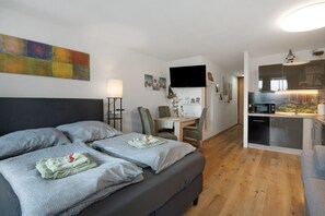 Ein modernes Schlafzimmer mit einem großen Bett, einem Schreibtisch und einer Küchenzeile.