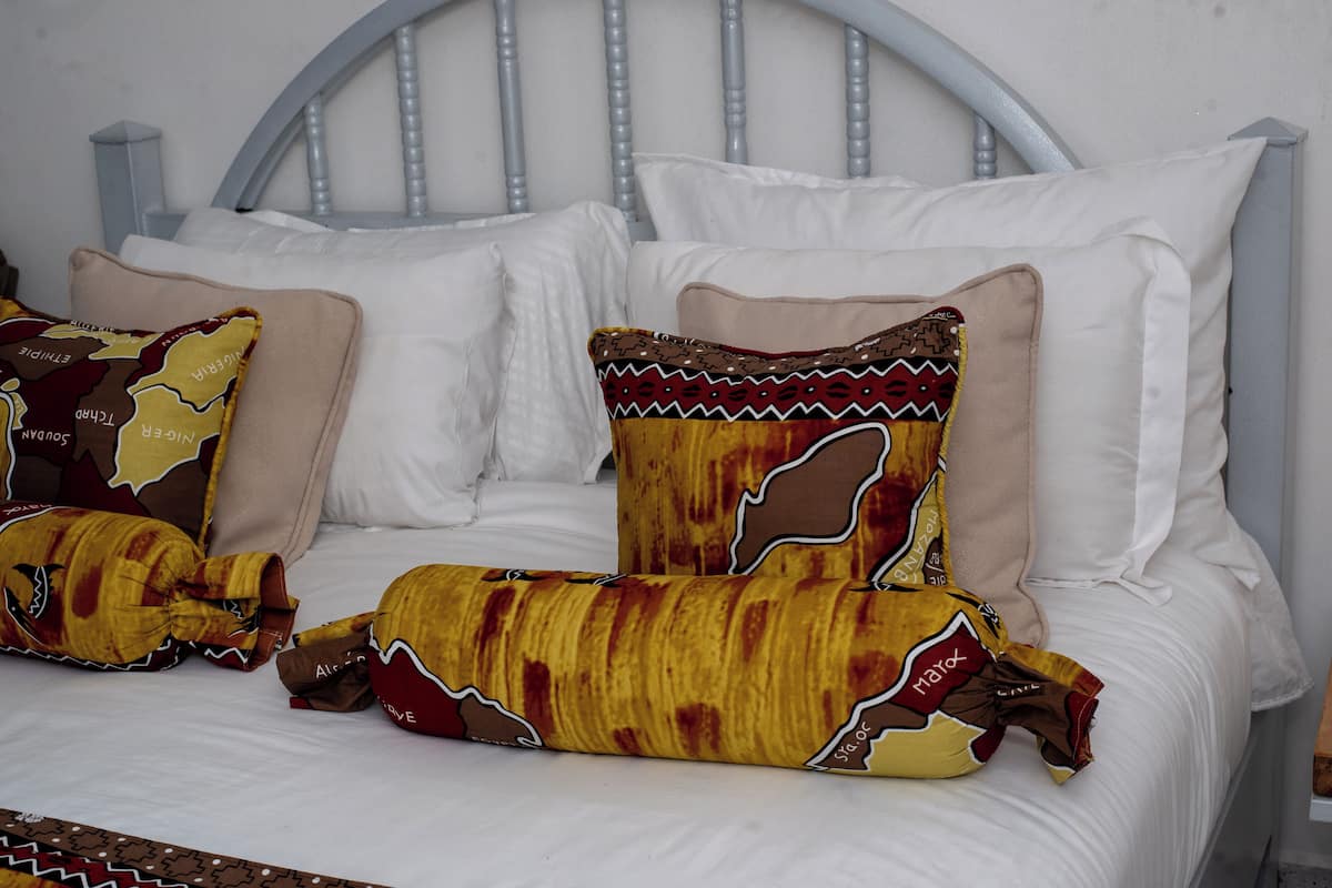 Ein Bett mit weißer Bettwäsche und gemusterten Kissen.