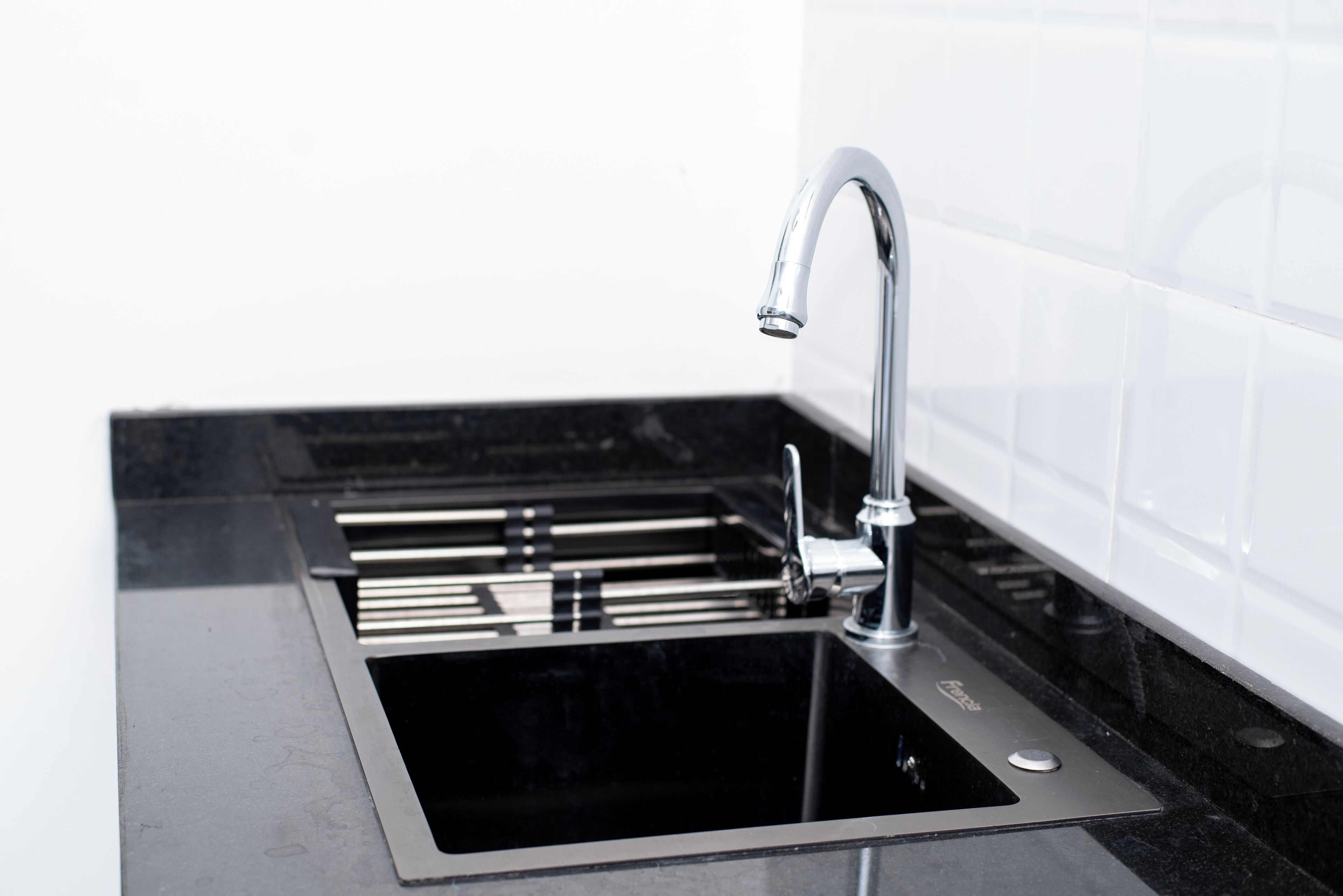 A modern kitchen with a stainless steel sink, a faucet, and a black countertop.