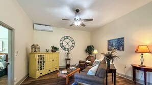 A living room with a sofa, coffee table, yellow cabinet, and a large wall clock.