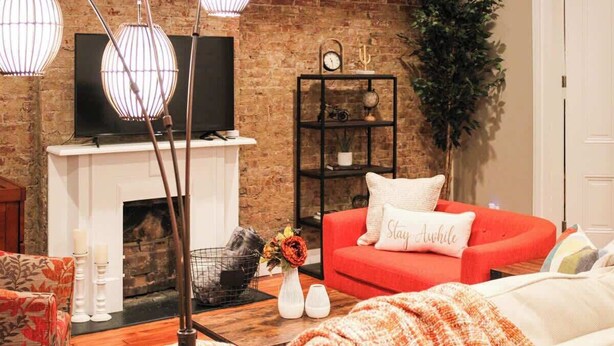 A living room with a brick wall, a fireplace, a red sofa, and a television.