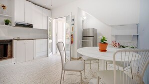 Une cuisine moderne avec des meubles blancs, une table à manger avec des chaises et une plante en pot.