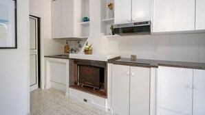Une cuisine moderne avec des meubles blancs, un four à micro-ondes encastré et une cheminée.