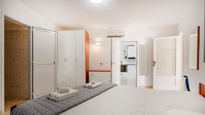 Une chambre d’hôtel avec un lit, une armoire et une salle de bain visible à travers une porte ouverte.