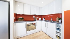 Een moderne keuken met witte kasten, een houten aanrecht en een ingebouwde oven.