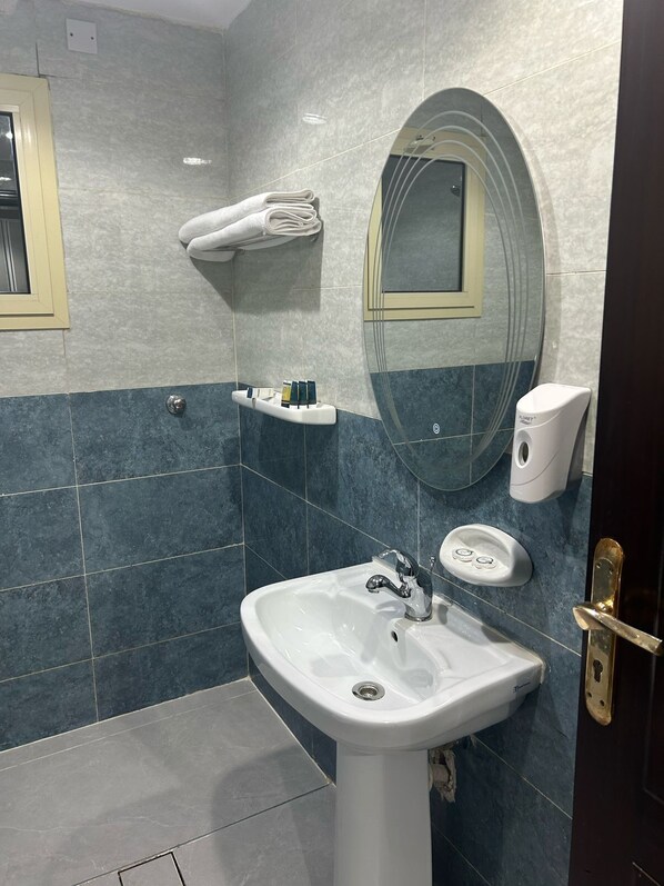 A modern bathroom with a white sink, a mirror, and a towel rack.