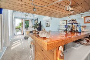 A modern kitchen with a wooden countertop, a ceiling fan, and a view of the outdoors.