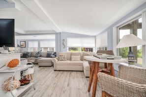 A spacious living area with a sofa, a round table, and a television.