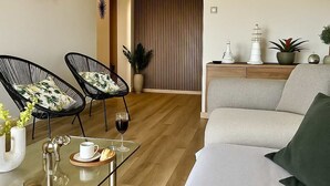 A modern living room with a sofa, two chairs, a glass coffee table, and a decorative wall piece.
