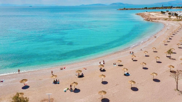 A beach with umbrellas and people.