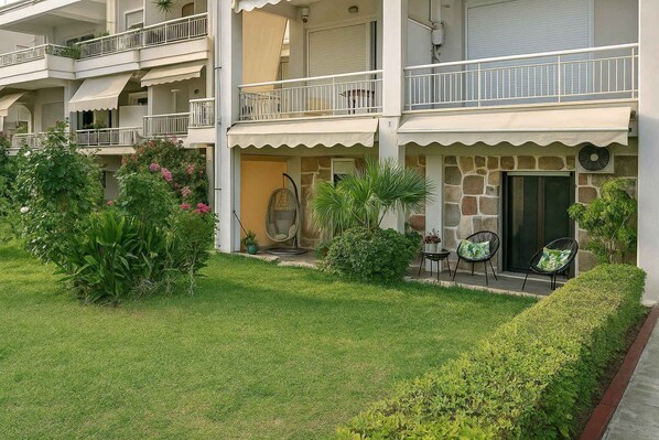 A multi-story building with balconies, a stone facade, and a well-maintained garden. - Beachside Retreat in Glyfada (Glifada)