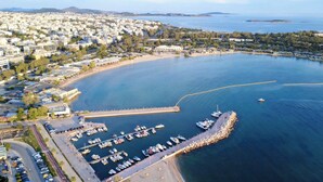 An aerial view of a coastal city with a marina, a curved road, and residential buildings.