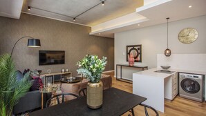 A modern living space with a dining area, kitchen, and laundry area. - The Docklands Executive Apartment (Cape Town)
