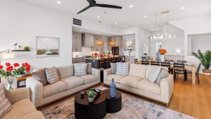A modern living room with two sofas, a coffee table, and a dining area with a chandelier.