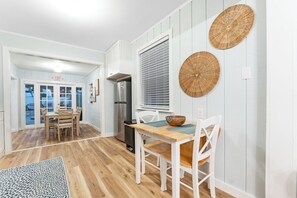 A modern kitchen with a wooden table, white chairs, a refrigerator, and a window with blinds. - 3Bdrm, Pool/Spa, private oasis (Indian Rocks Beach)